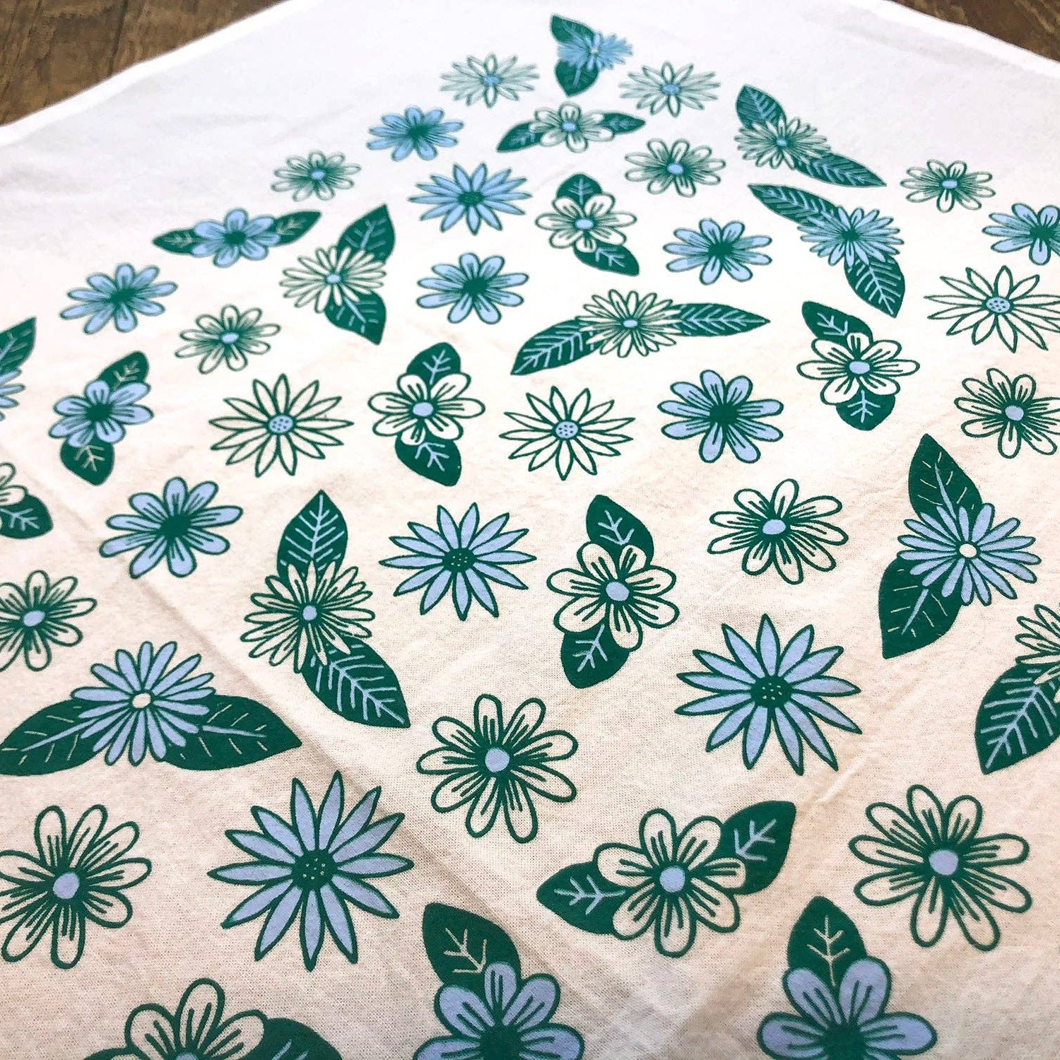 Floral patterned fabric with green and blue flowers on a beige background